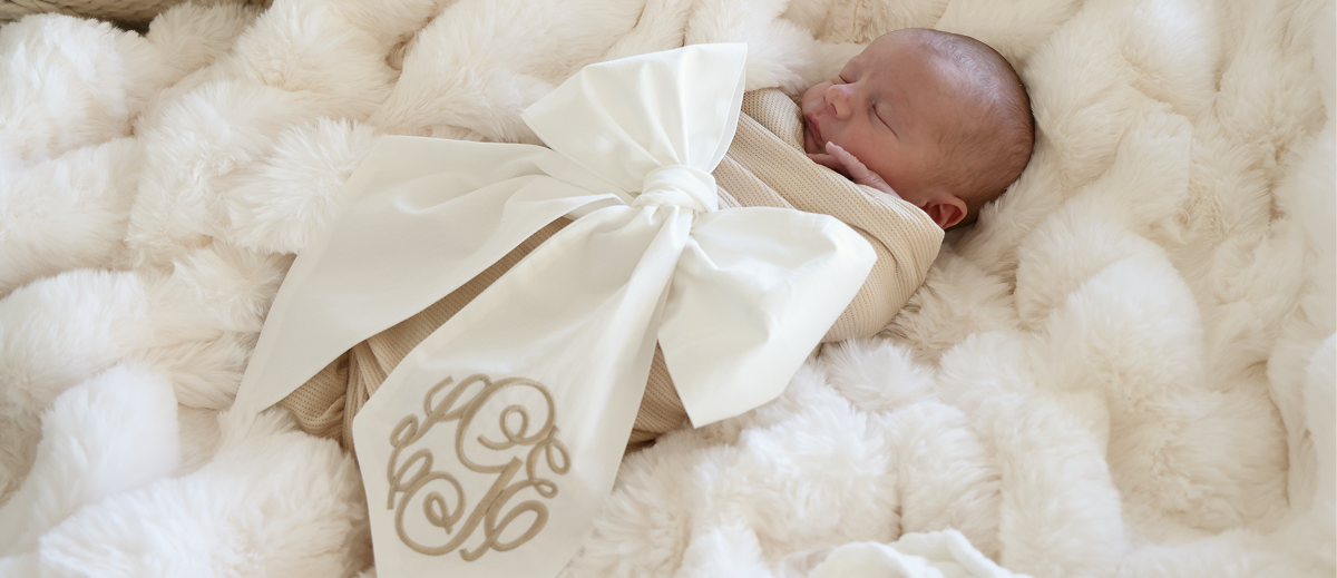 baby wearing Caden Lane white embroidered bow sash
