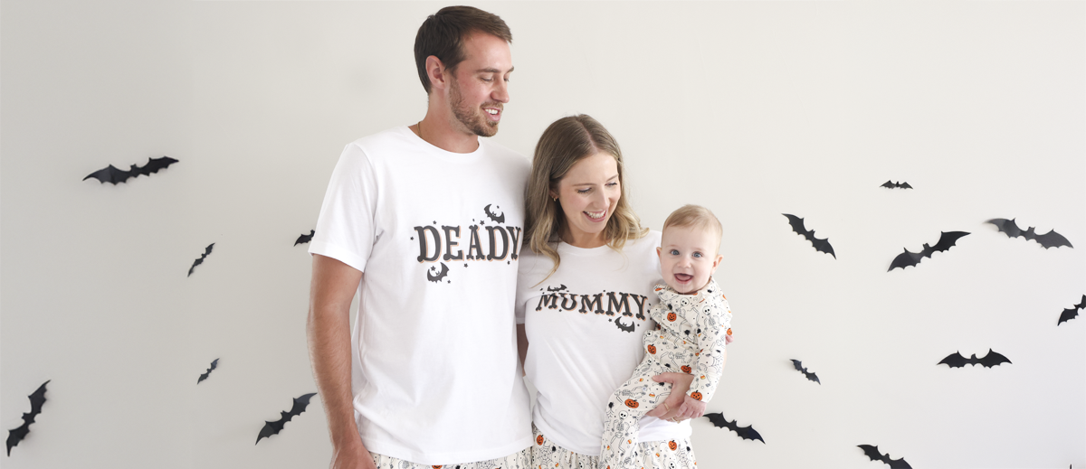 Mom, dad and baby in Caden Lane's family-matching Halloween pajamas