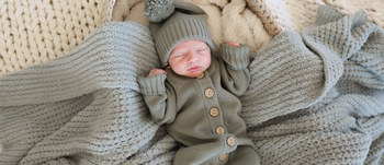 Newborn wearing Caden Lane knit sweater button romper and pom pom beanie