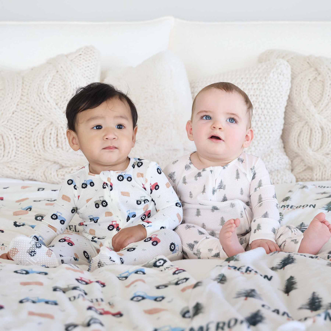 Baby on left wearing little farmer waffle footie and baby on right wearing the Evergreen zip romper 