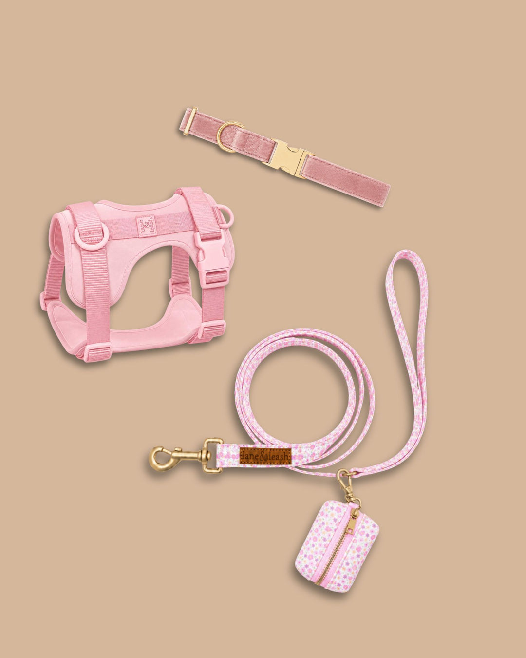 Caden Lane ballet slipper pink pet accessory set including velvet collar, strap harness, leash, and waste bag holder on tan background