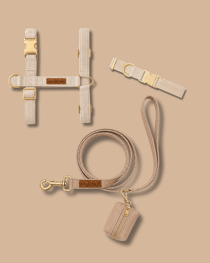 Caden Lane sand dune beige flax fabric pet accessory set including strap harness, collar, leash, and waste bag holder on tan background