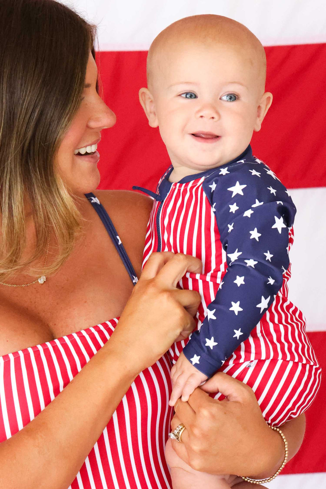 mom holding son wearing matching stars & stripes 4th of july swimsuits