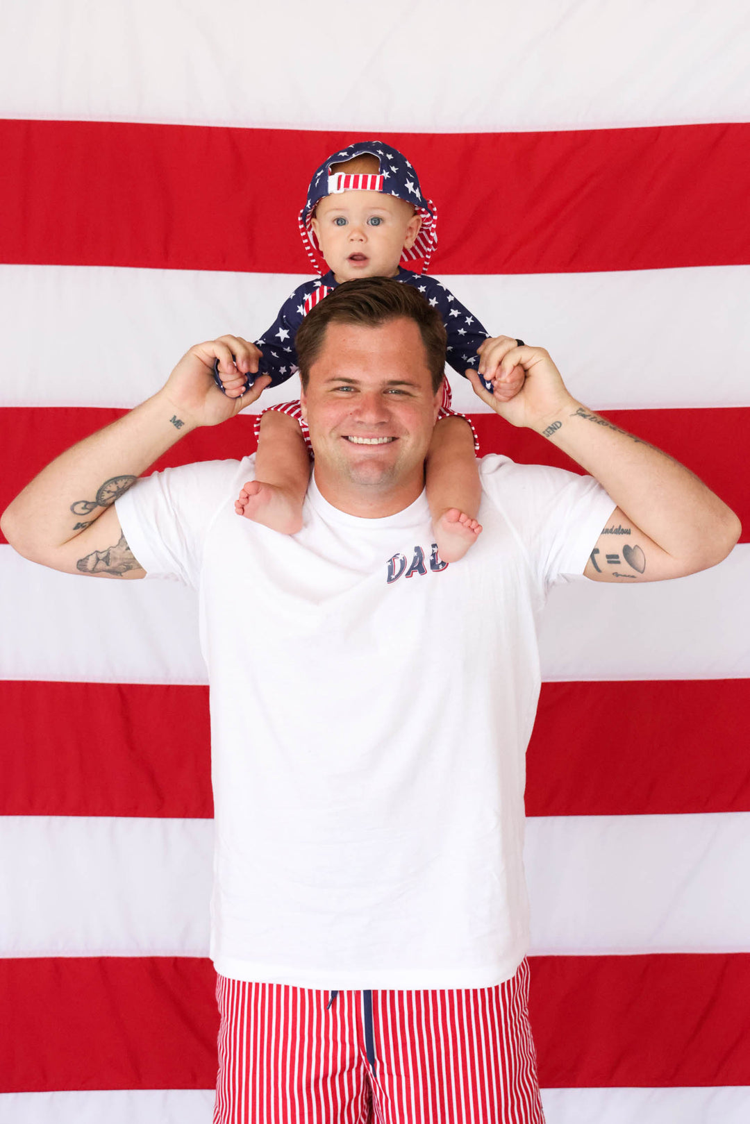 boy sitting on dad's shoulders in 4th of july matching swimwear