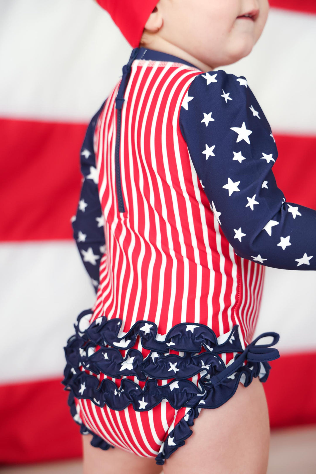 Baby girl rash guard with ruffle bottom flat lay | USA patriotic swim | UPF 50+ kids swimwear | Caden Lane