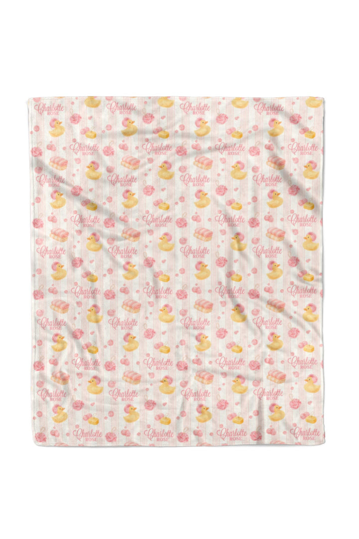 Child smiling and holding 50x60 pink Bubble Duckies personalized blanket with yellow rubber duck and pink rose print