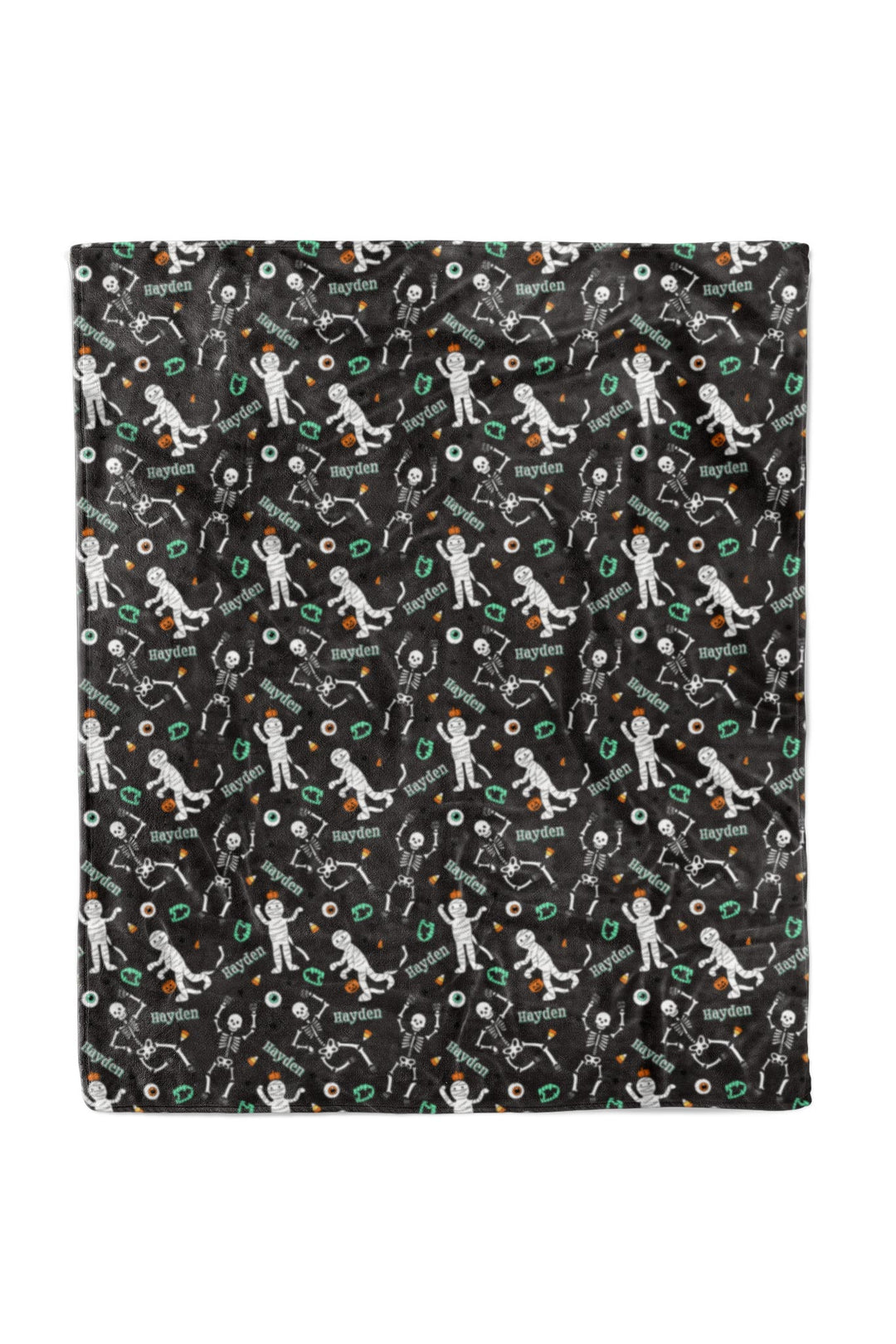 Close-up of black blanket fabric personalized with the name 'Hayden' repeated throughout, along with Halloween skeleton graphics.