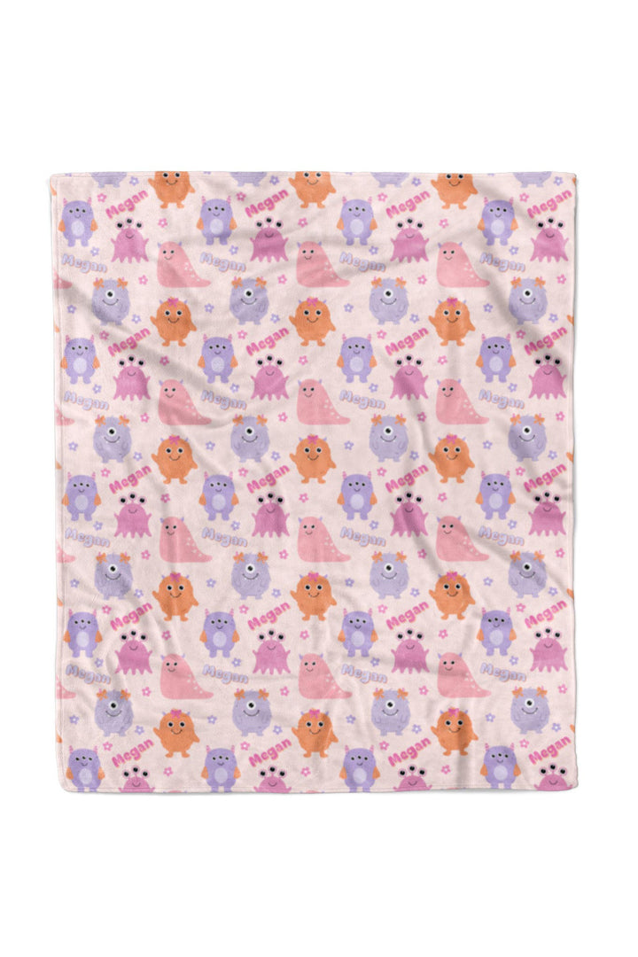 Caden Lane 50x60 personalized "Megan" minky blanket in Little Monsters print with pink, purple, and orange cartoon monsters and flowers