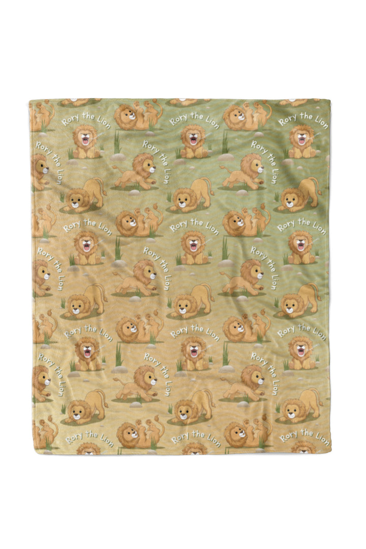 Flat lay of a Caden Lane personalized "Rory the Lion" fleece baby blanket in a green-to-tan ombre pattern, covered in a repeating print of a playful lion character in different poses with "Rory the Lion" text arched throughout