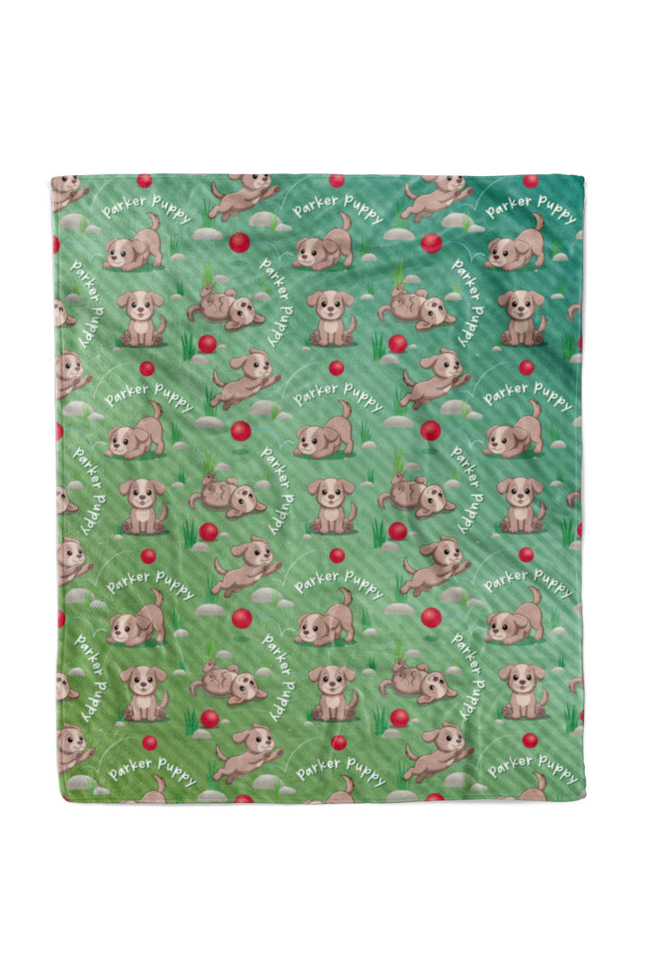 Flat lay of a Caden Lane personalized "Parker Puppy" fleece baby blanket in a green ombre pattern, covered in a repeating print of a playful puppy character with a red ball and "Parker Puppy" text arched throughout