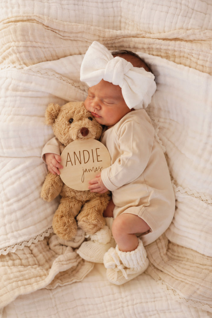 newborn holding teddy bear and wood name announcement block and script font