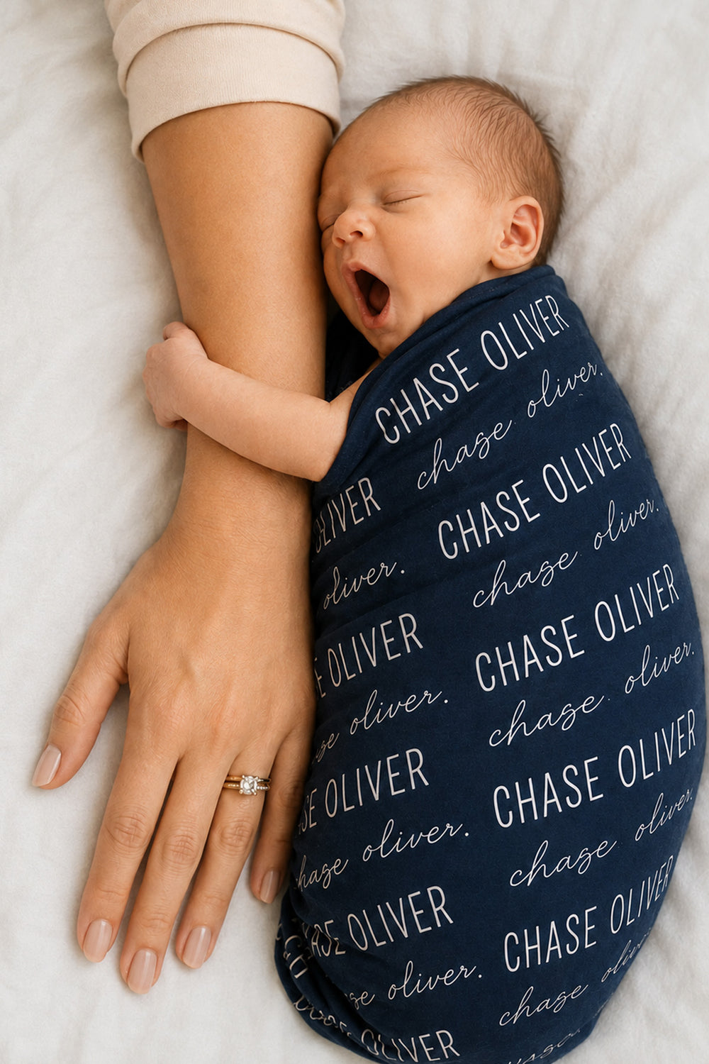 newborn wrapped in personalized midnight baby name swaddle blanket block and script 