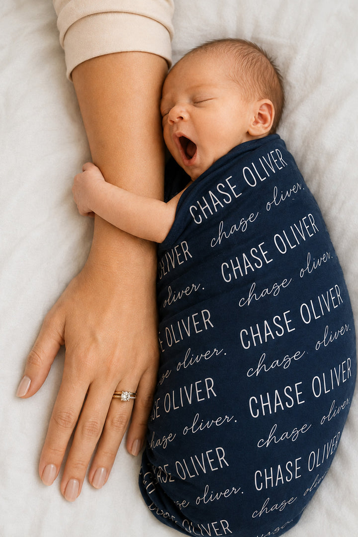 newborn wrapped in personalized midnight baby name swaddle blanket block and script 