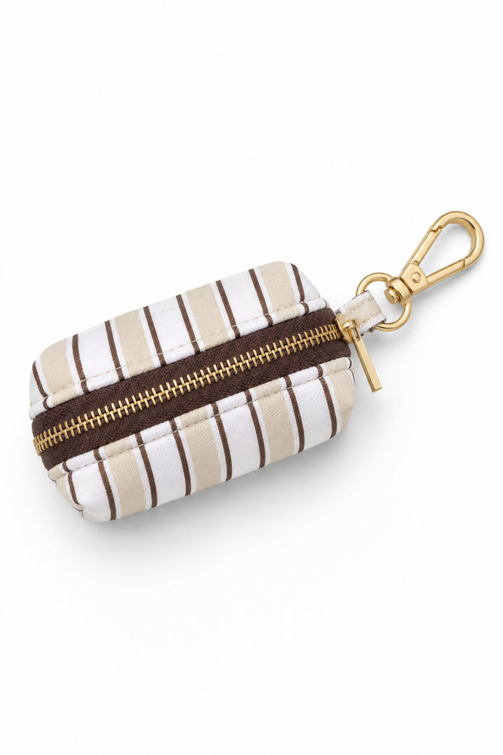 Pet waste bag holder in Biscuit Stripe pattern with tan and white vertical stripes, featuring a gold-tone carabiner clip and dark zipper closure