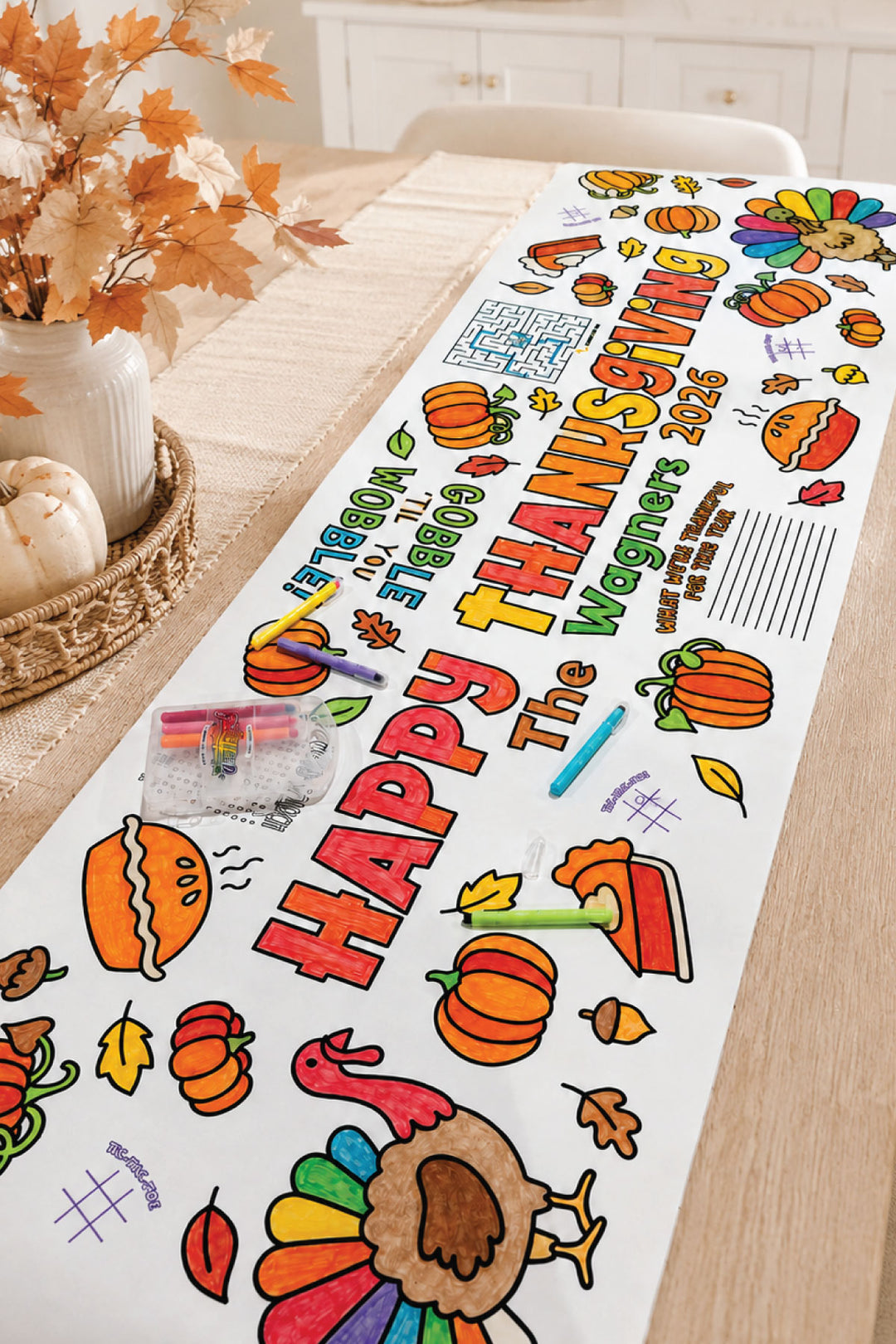 Colored-in personalized Happy Thanksgiving activity banner on a dining table with markers, pumpkins, and a turkey