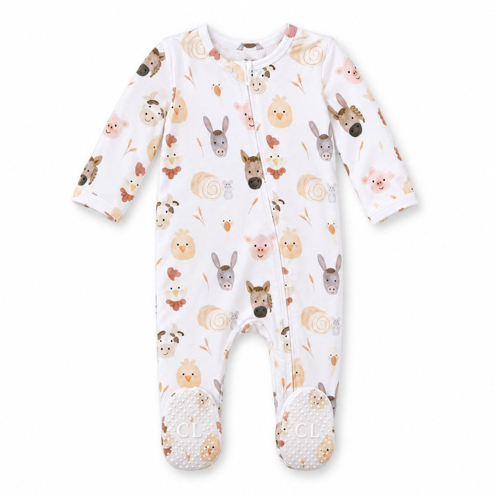 Flat lay of a Caden Lane white bamboo zipper footie in a Barnyard Buddies print featuring watercolor horses, donkeys, pigs, chicks, and hay bales, with gripper soles.