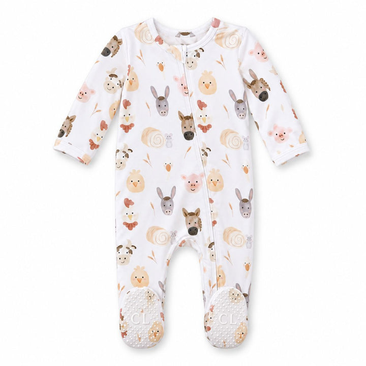 Flat lay of a Caden Lane white bamboo zipper footie in a Barnyard Buddies print featuring watercolor horses, donkeys, pigs, chicks, and hay bales, with gripper soles.