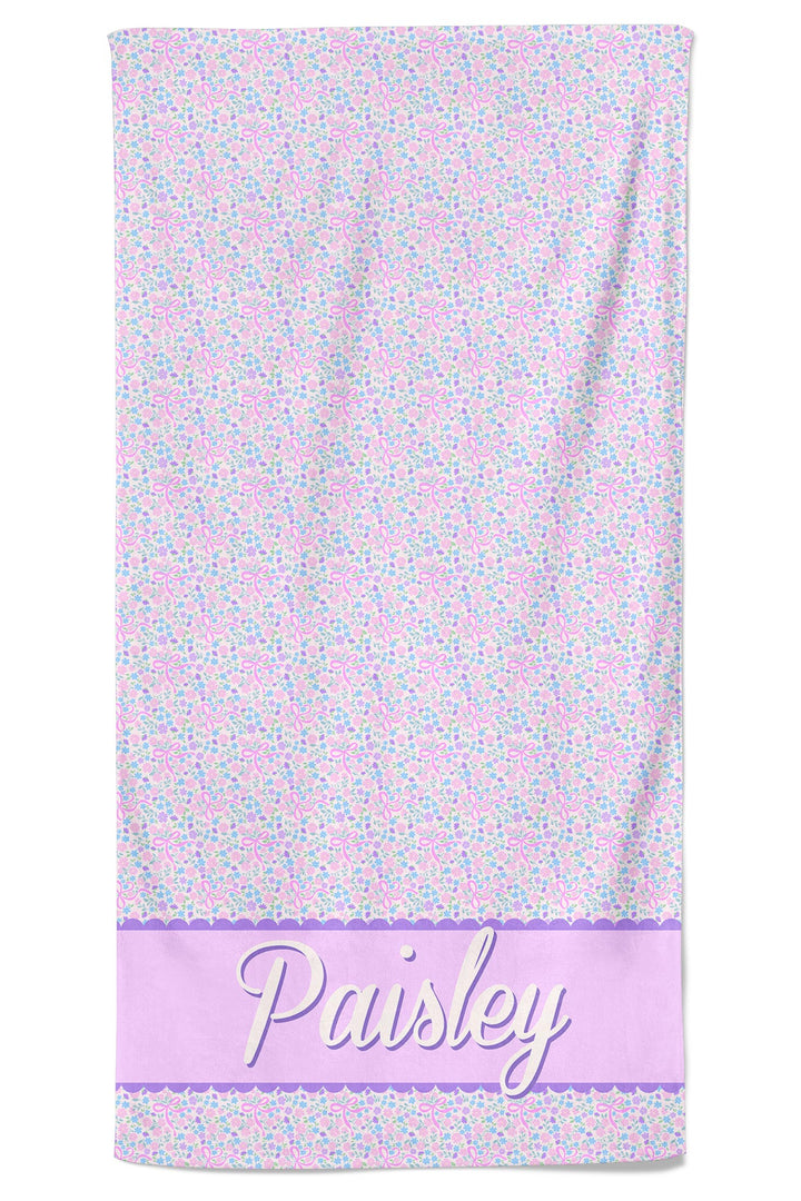Personalized pet towel in the Ribbon Garden print — pink floral pattern with a lavender stripe at the bottom — personalized with the name "Paisley" in script font, shown hanging flat