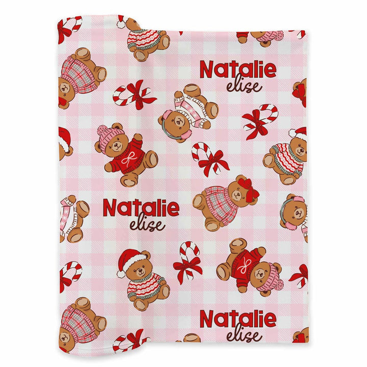 pink gingham personalized swaddle blanket for baby girls with teddy bears dressed in christmas sweater with santa hats and bows with candy canes scattered throughout