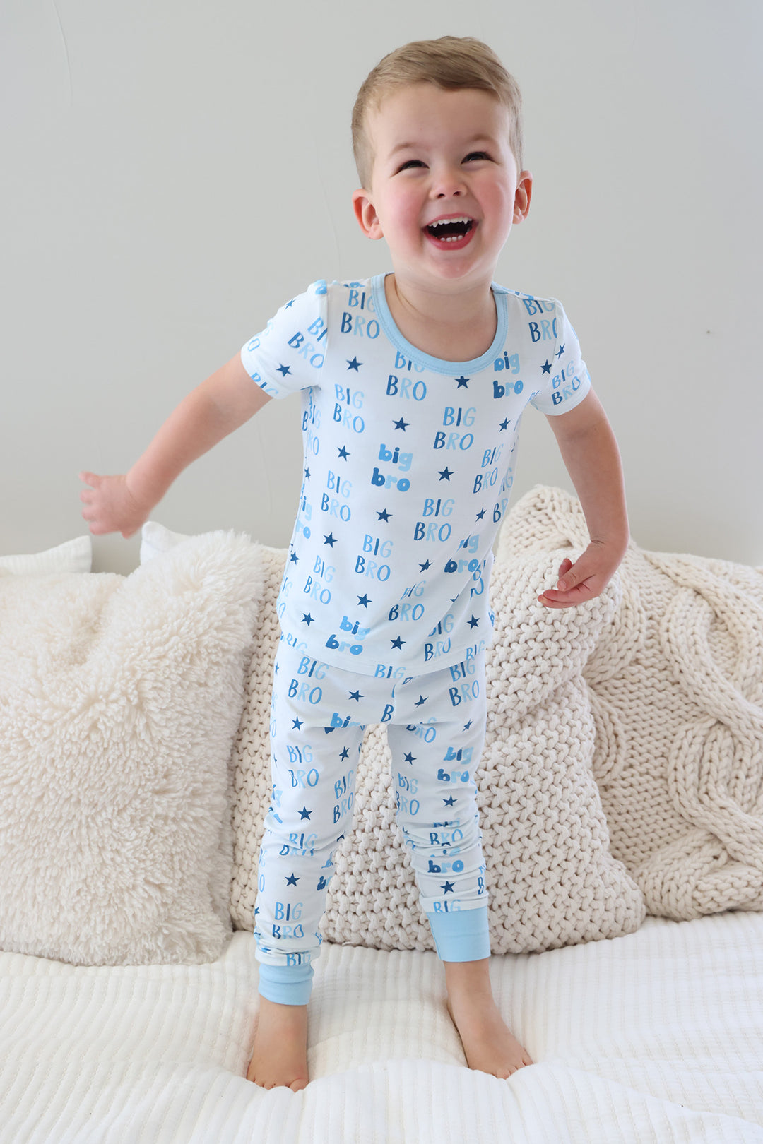 laughing boy jumping on the bed in blue star big bro two piece pajama set with short sleeves and pants 
