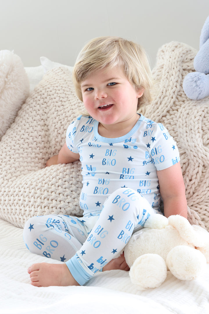 boy sitting on bed criss cross in big bro star two piece pajama set 