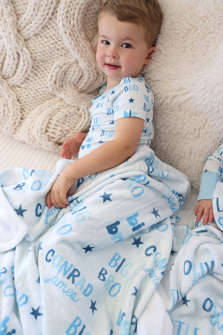 boy laying on his side in big bro pajama set with personalized matching blanket over him 