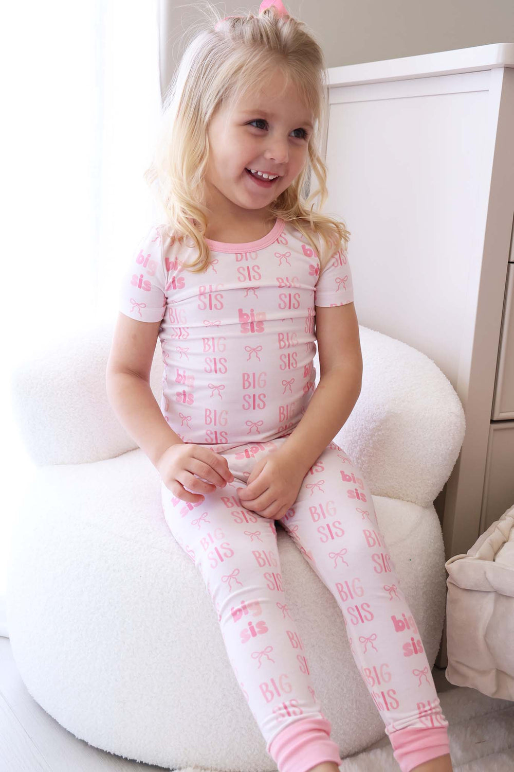 girl sitting on chair in big sis bow two piece pajama set with short sleeves and pants 