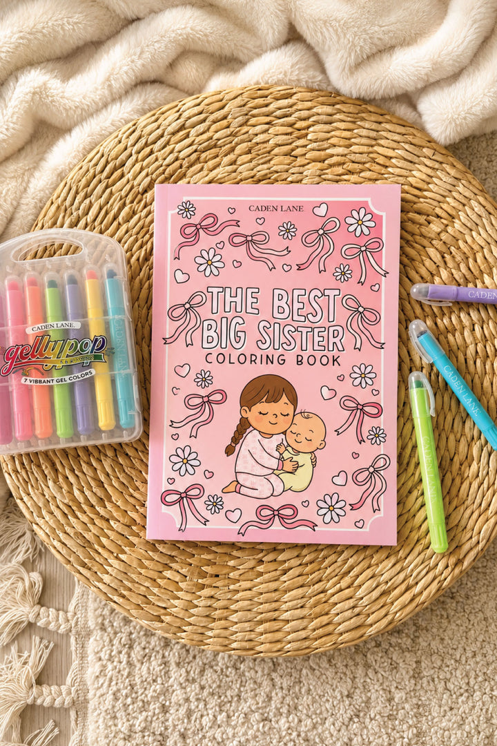 The Best Big Sister" coloring book in pink with bows and daisies, styled with Gellypop gel crayons on a woven tray.