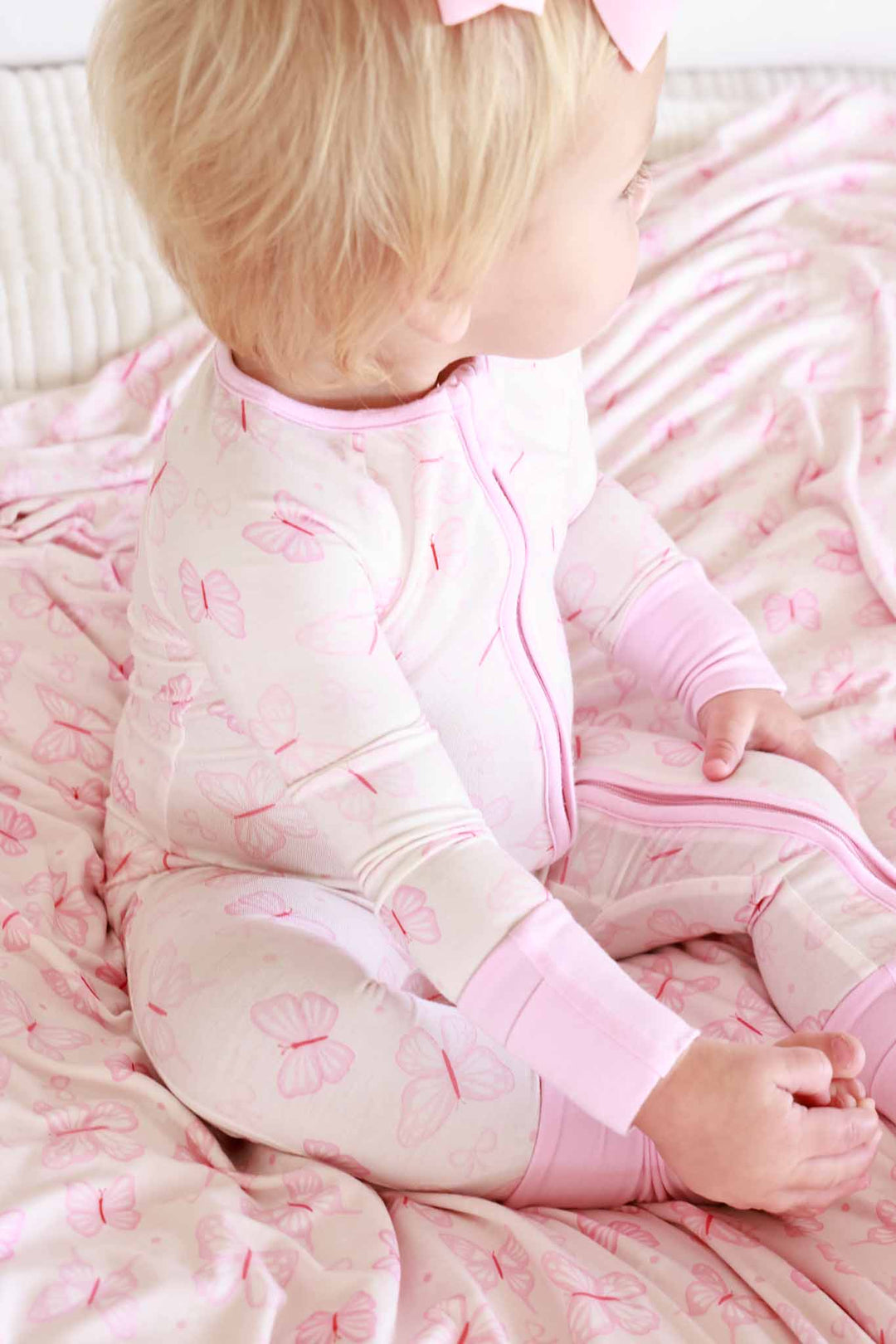 Convertible Zip Romper in Blooming Butterflies print - close-up of toddler wearing the romper, showing the front zipper detail and pink cuffed wrists with butterfly print fabric