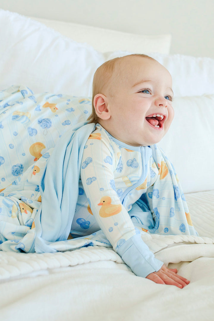 Two babies side by side wearing blue and pink Bubble Duckies convertible zip romper pajamas with rubber duck print