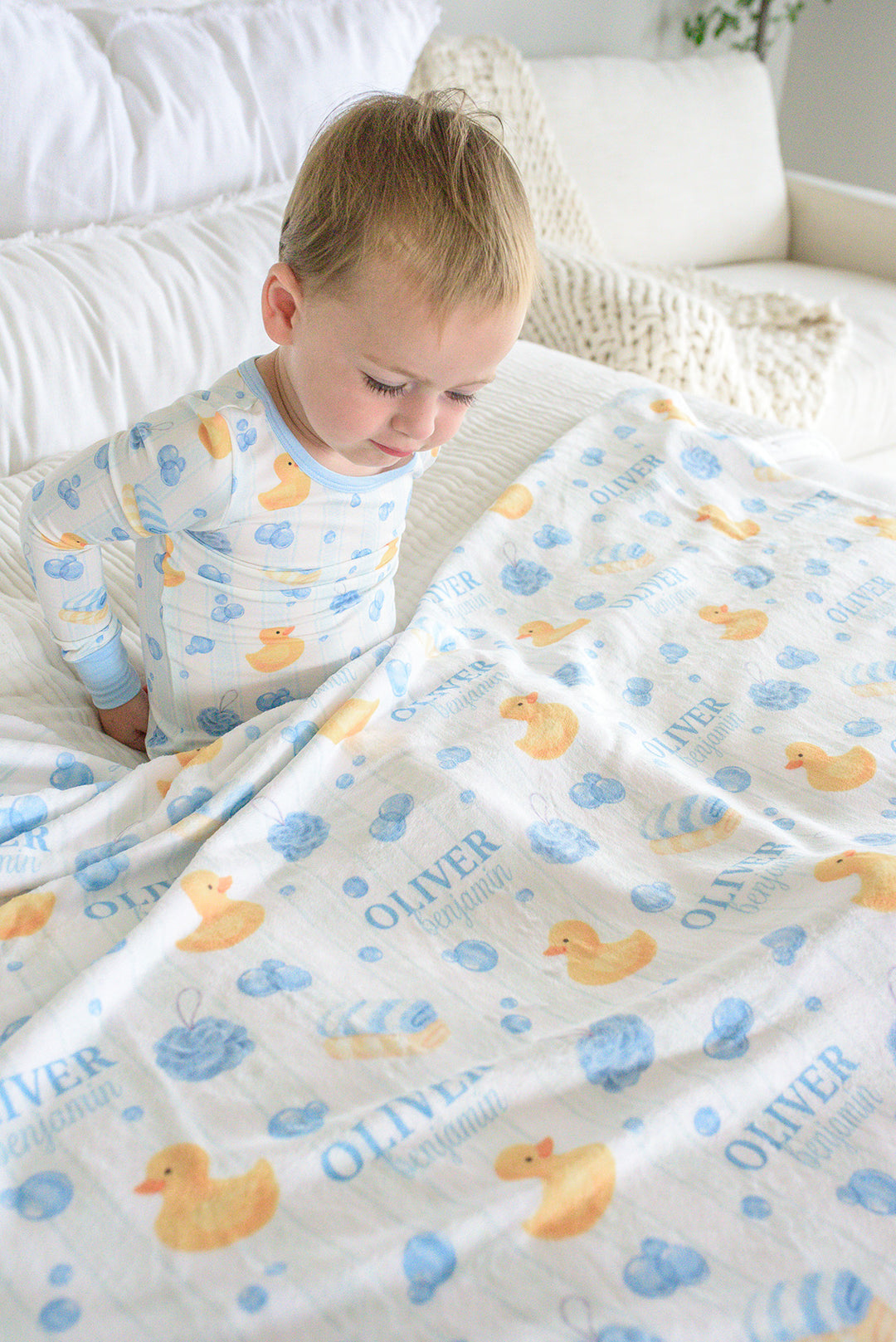 Boy wrapped in blue Bubble Duckies personalized blanket with rubber duck and blue bubble print and monogram name