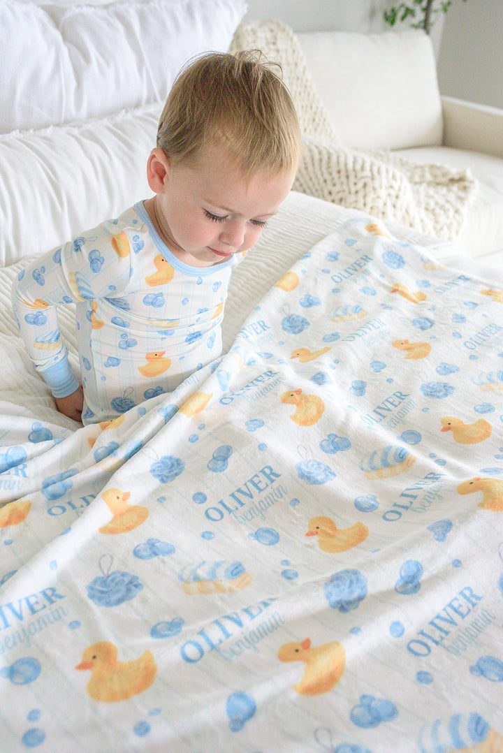 Boy wrapped in blue Bubble Duckies personalized blanket with rubber duck and blue bubble print and monogram name