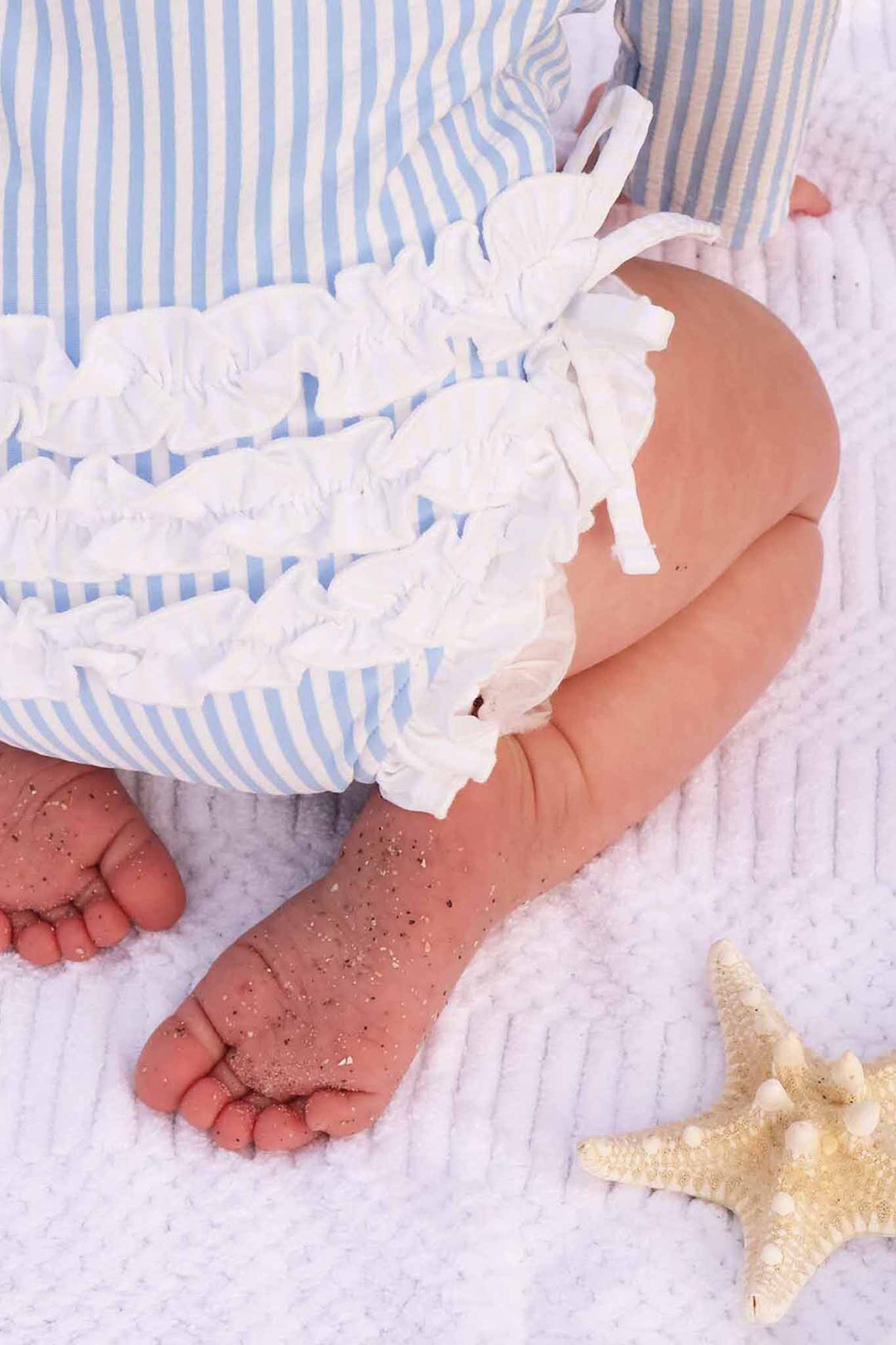closeup of ruffle bottom rash guard swimsuit in blue seersucker 