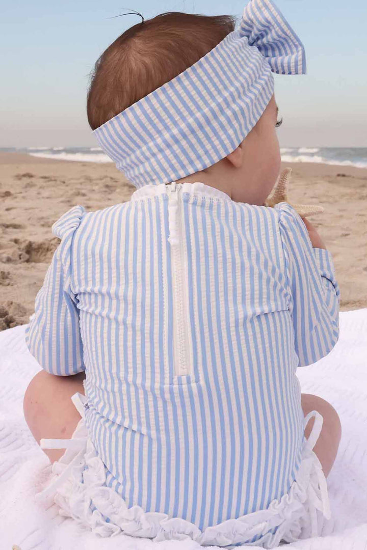 back view of blue seersucker ruffle bottom rash guard swimsuit for baby girls 