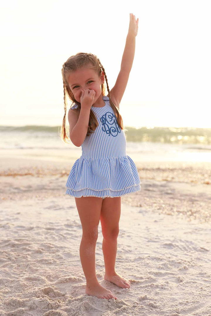 girl standing with her nose plugged at the beach in blue seersucker monogrammed one piece 