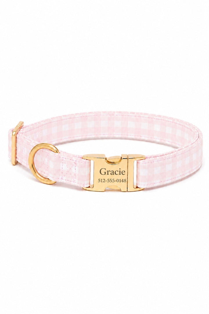 A Lane & Leash pink and white gingham check dog collar with a gold-tone metal buckle engraved with the name 'Gracie' and a phone number, shown on a plain white background.