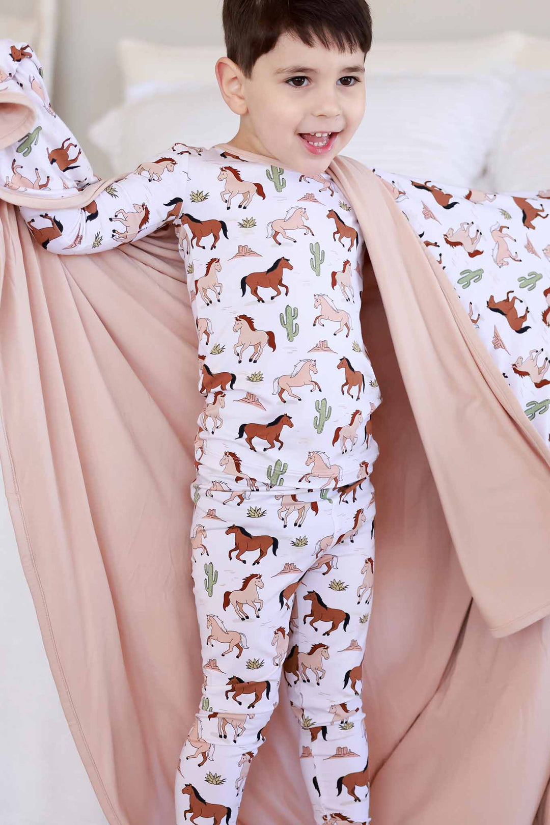 boy wearing boy pony club two piece pajama set with bamboo blanket wrapped around him 