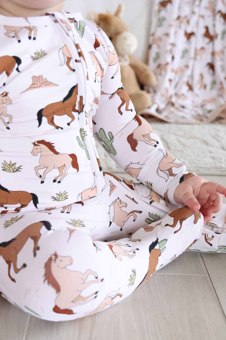 neutral pony club zipper footie with horses and cacti