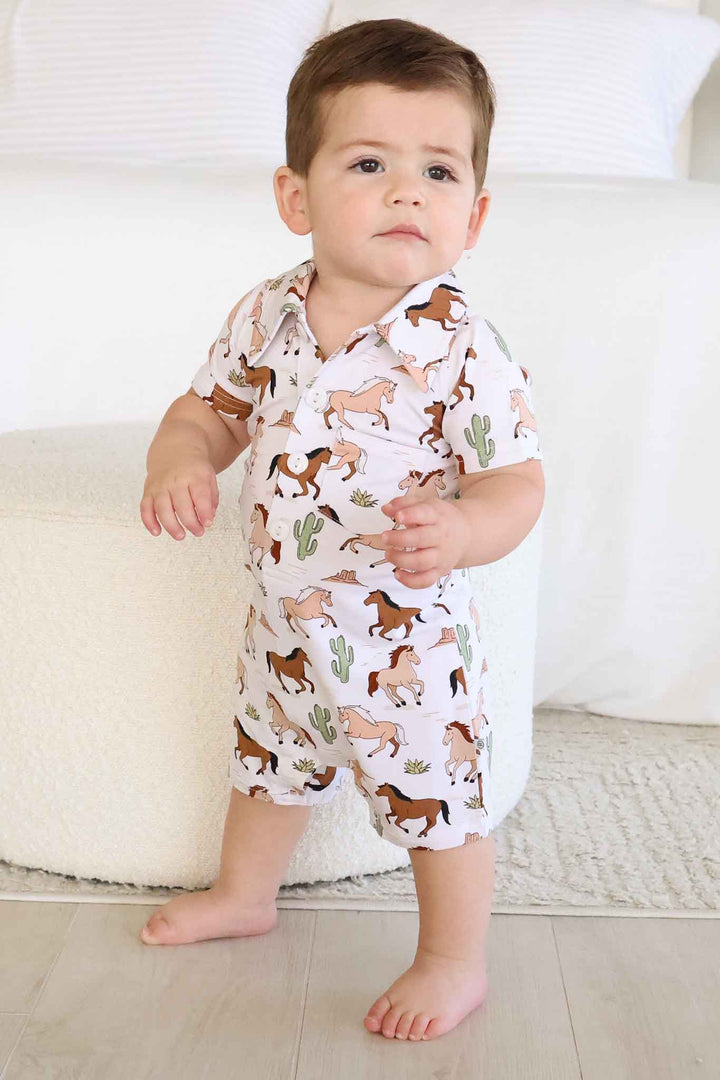 standing baby boy in horse and cactus button romper 