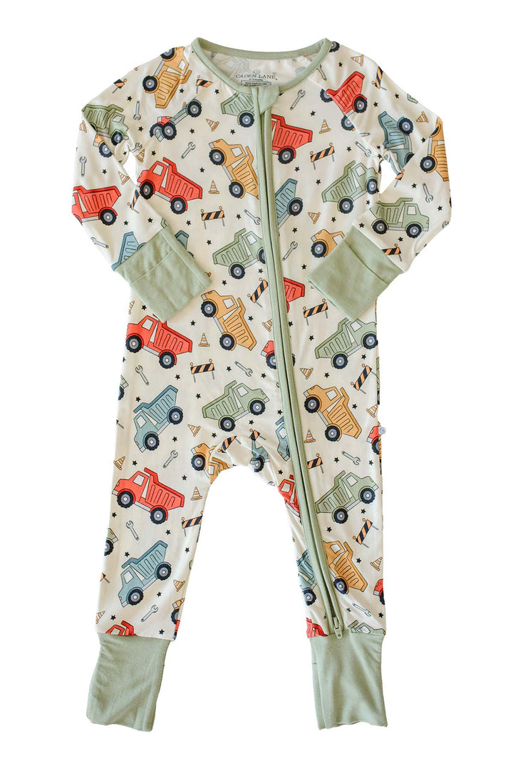 Flat lay of a Caden Lane cream knit zip romper in a Busy Builder print featuring dump trucks and barricades, with sage zipper trim and fold-over cuffs.