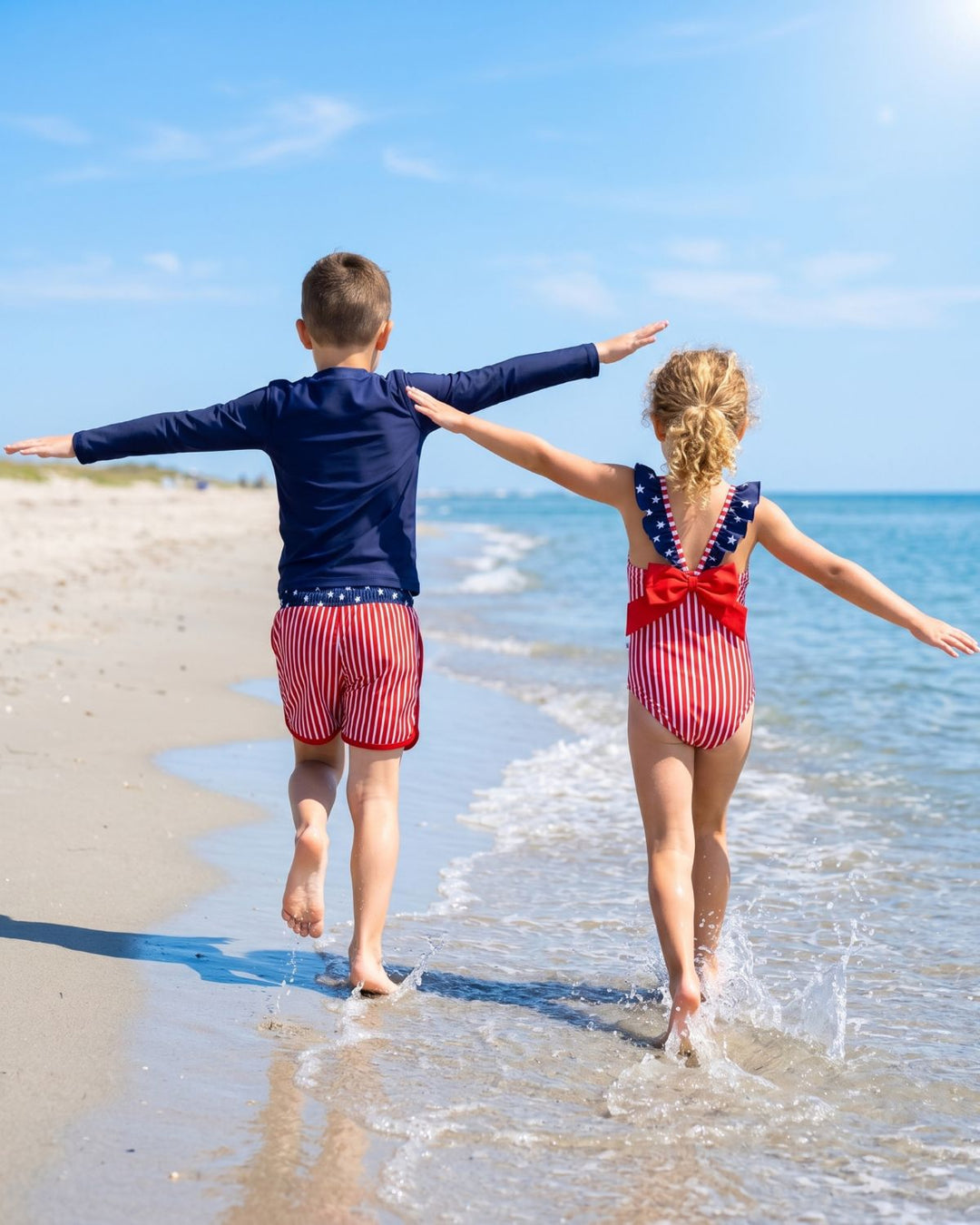 back view of sibling walking on the beach in american flag swimsuits 