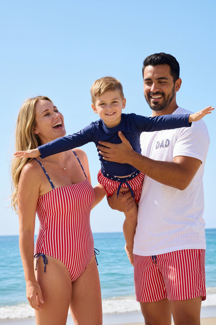 mom and dad playing with son on the beach in navy long sleeve rash guard shirt 