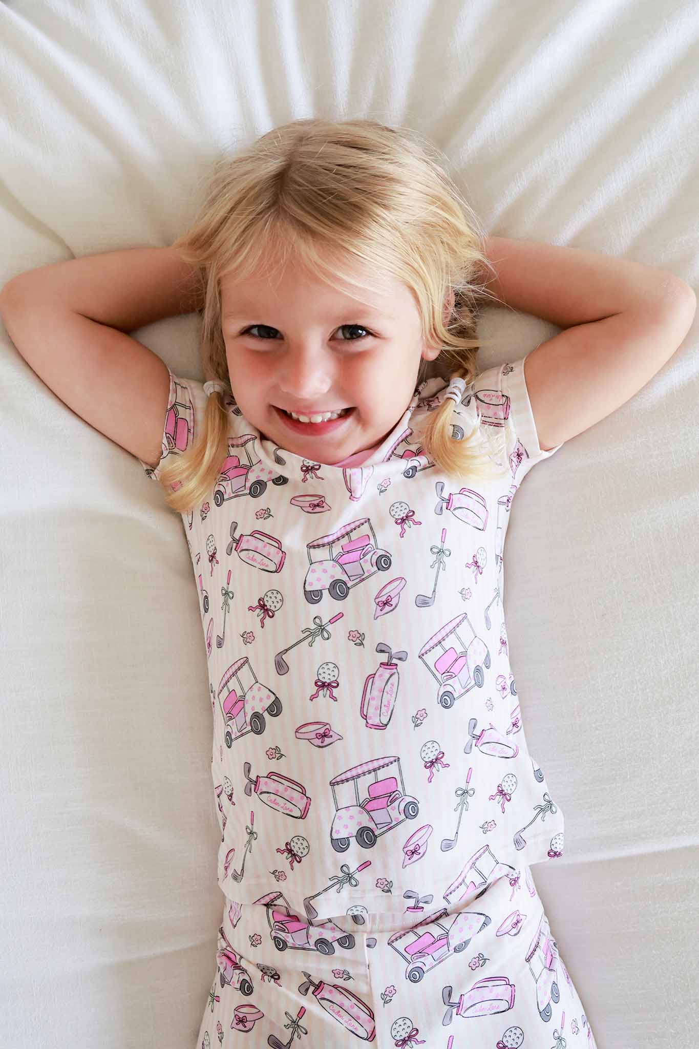 girl laying on bed in caddie crew pink 2pc pajama set