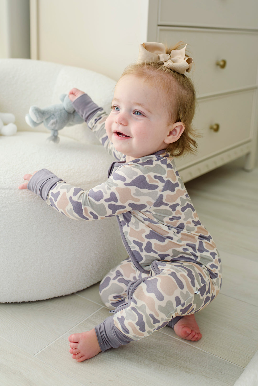 Camo cutie convertible zip romper on toddler from behind, sitting on rug