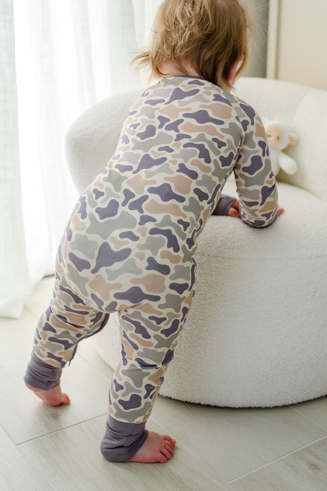 Camo cutie convertible zip romper from behind on baby toddler sitting on rug