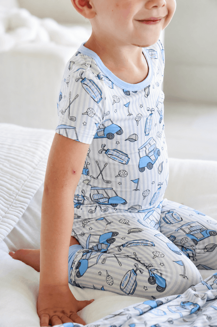 boy kneeling on bed in blue golf pajama set