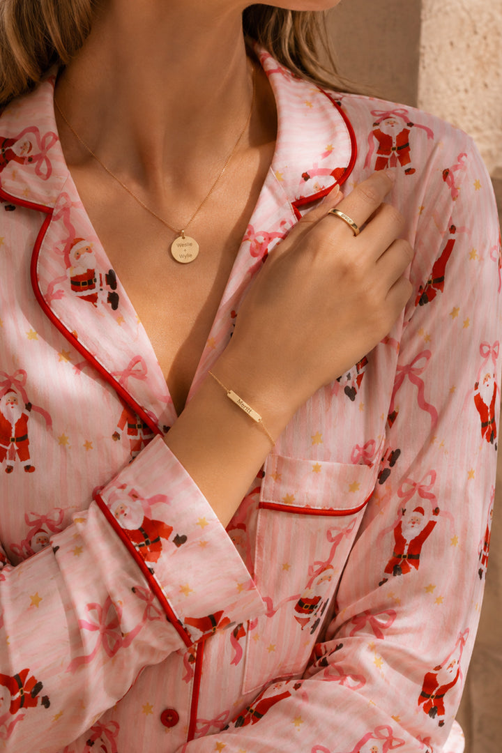 Caden Lane personalized gold jewelry with engraved name bracelet, initial ring, and disc necklace worn with a Santa print pajama set