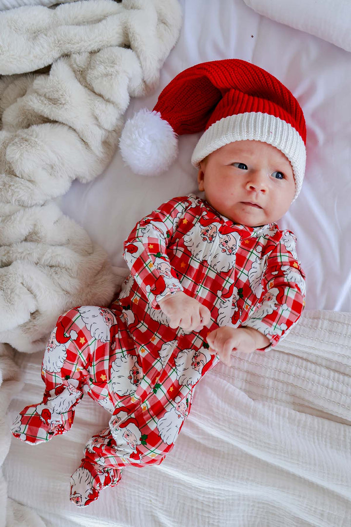 Caden Lane red and white knit Santa hat for babies with a soft ribbed knit, fold-over white cuff, and fluffy pom-pom. A cozy Christmas baby hat for newborns and infants, perfect for baby's first Christmas, holiday photos, Christmas pajamas, and festive outfits.