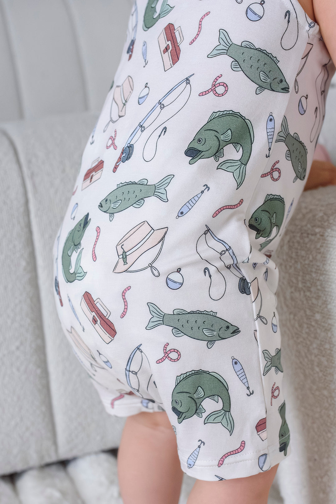 Close-up showing the snap closure at the bottom of the Off The Hook sleeveless snap romper with fishing print detail