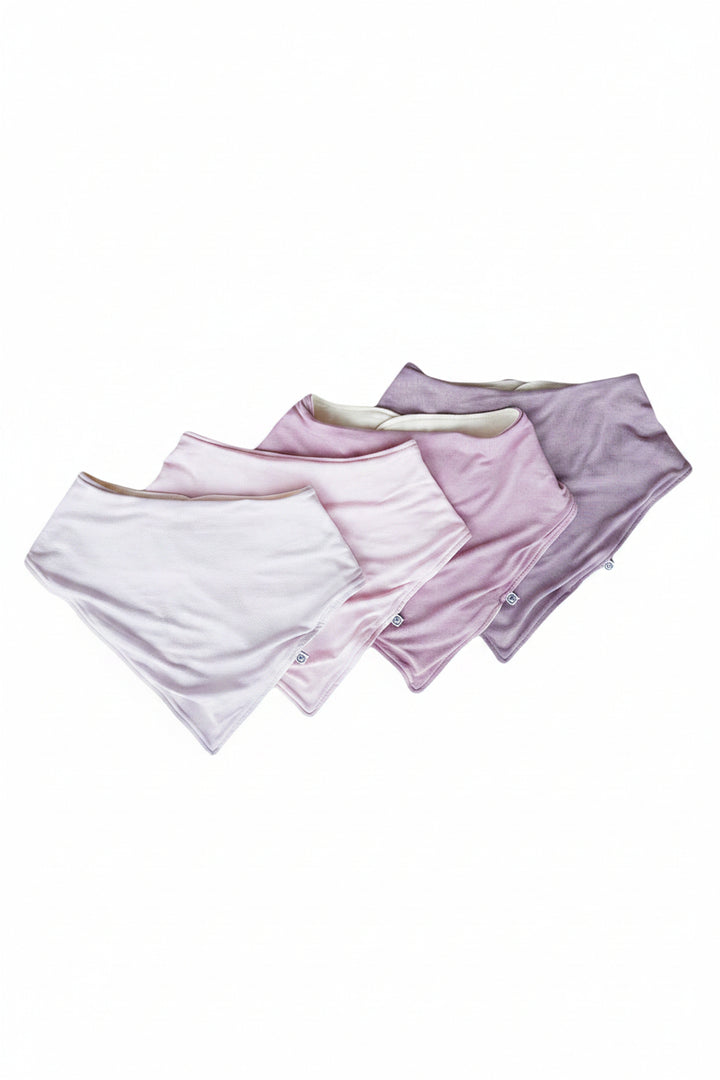 Four pairs of folded Caden Lane baby burp cloths  in white, pale purple, dusty purple, and lavender purple, arranged in a fan shape on a solid white background.